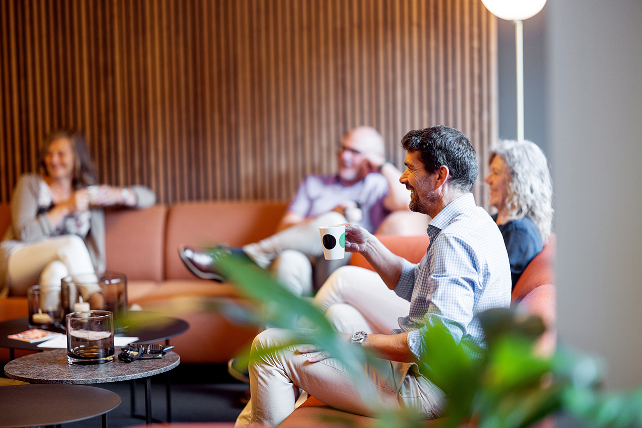 Kollegaer sitter i sofa og drikker kaffe