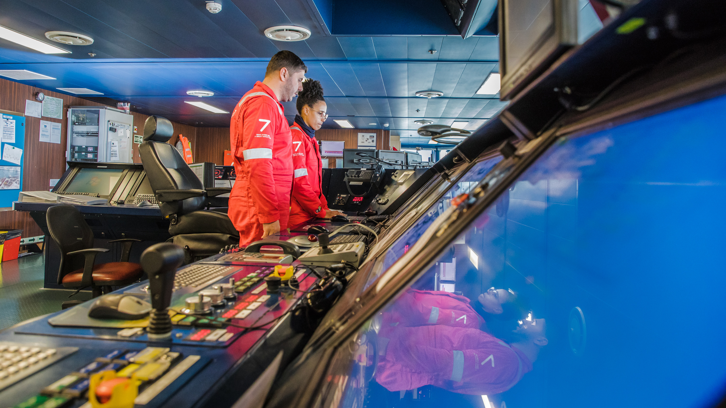 Image of two people in overalls in a control room