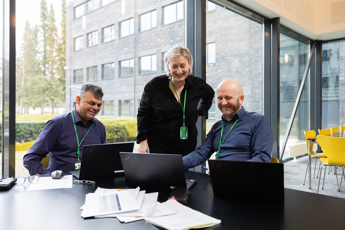Tre personer rundt et bord med PC